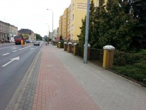 Ulica Surzyńskiego. Po prawej stronie - za drzewami wejście do Komendy i zaparkowany radiowóz sierżanta Toty